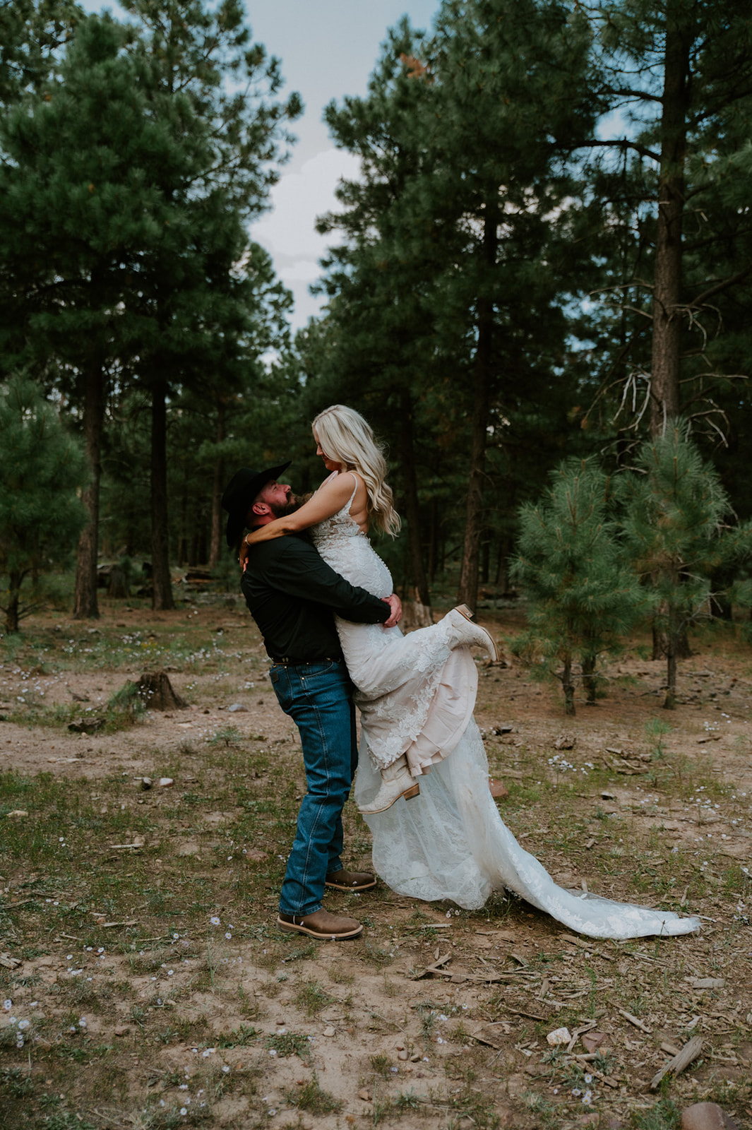 Couple celebrating after they elope in Arizona, surrounded by tall pine trees in a quiet forest clearing.