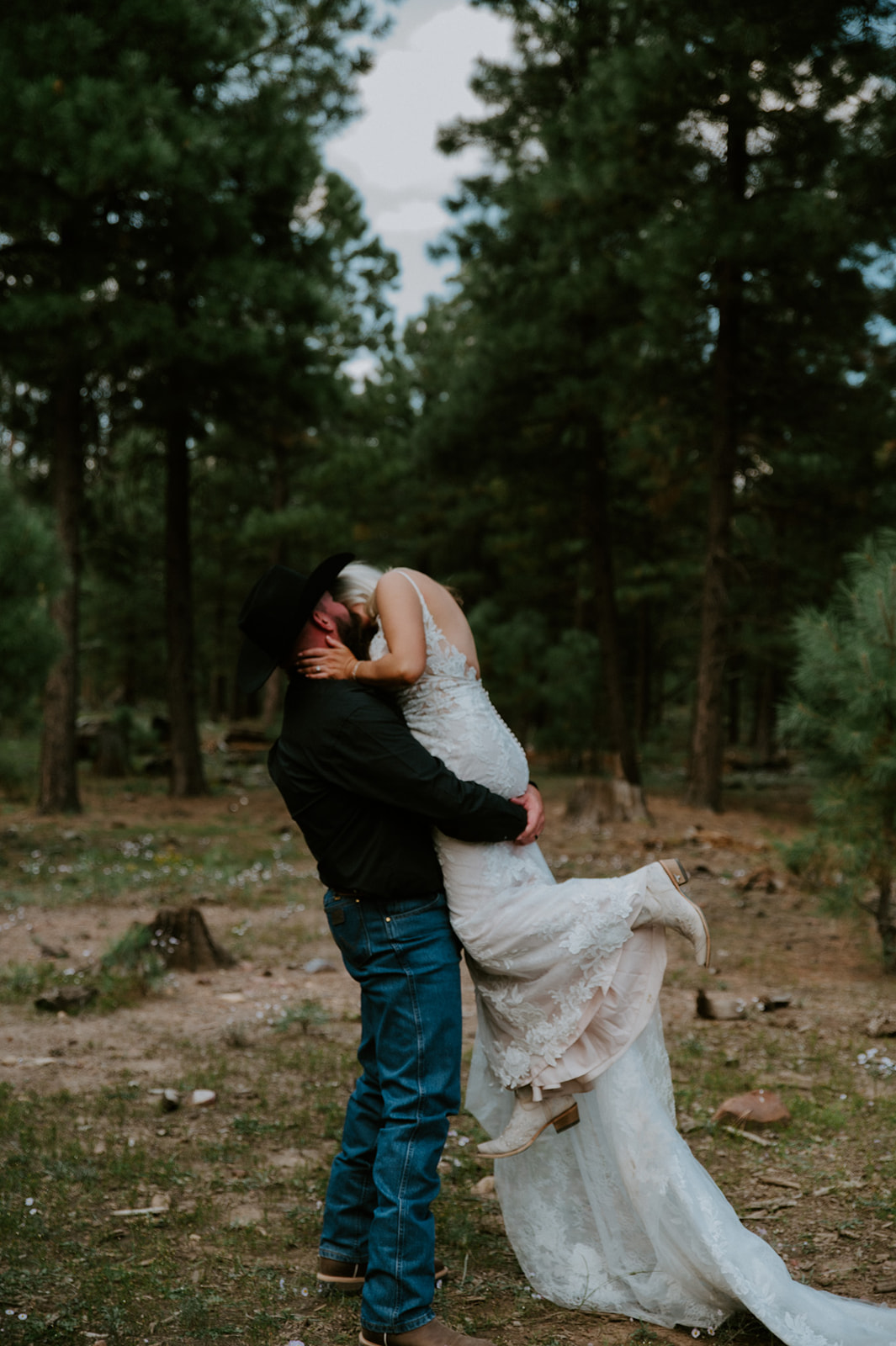 Groom lifting his bride in a secluded forest clearing after they elope in Arizona surrounded by tall pine trees.