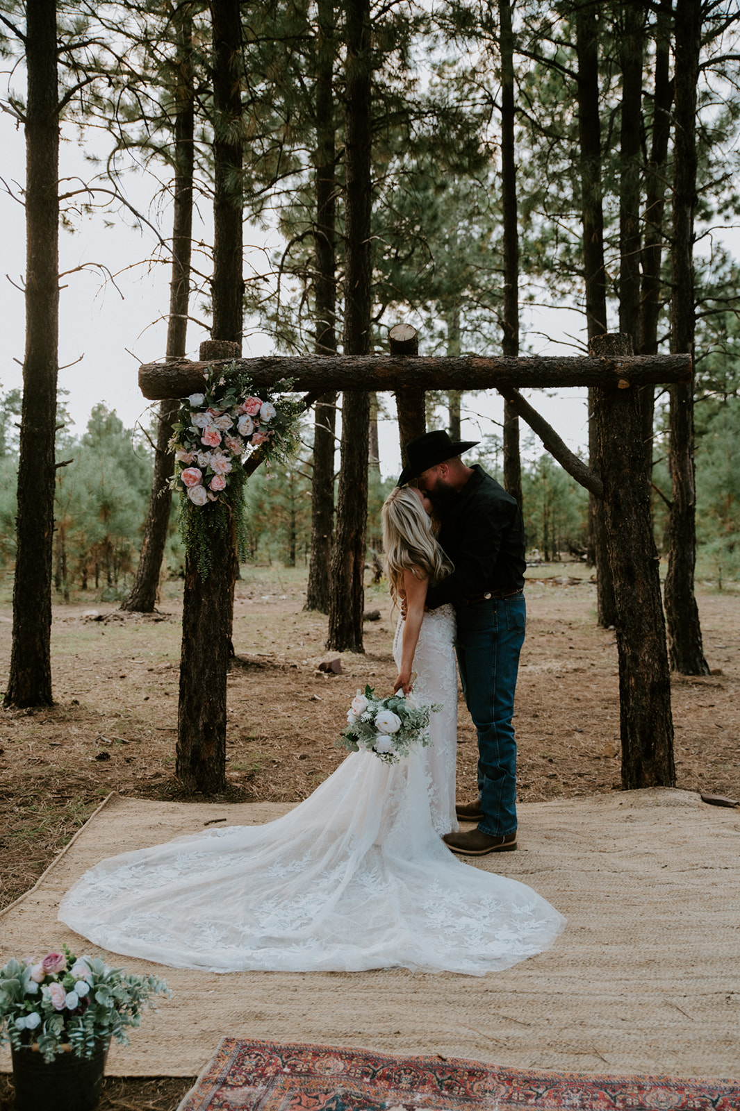 Rustic wooden ceremony arch decorated with florals in a private forest location for an Arizona elopement.