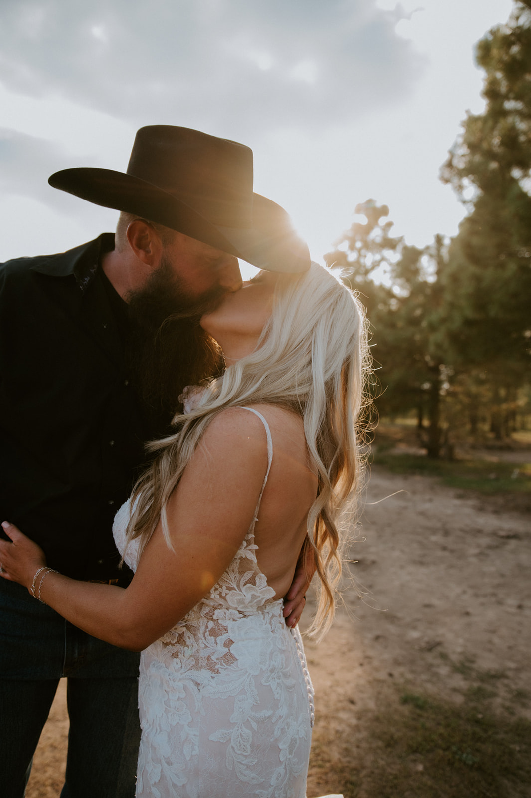 Golden hour portrait of a bride and groom kissing in the forest after choosing to elope in Arizona.