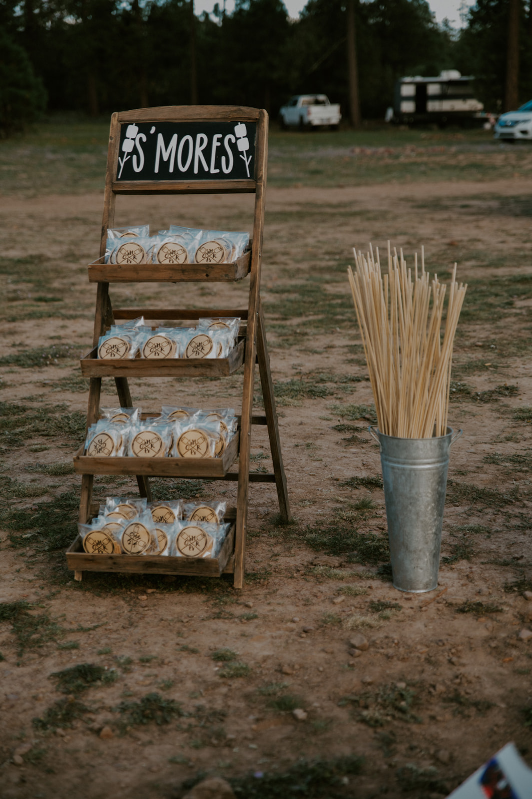 Rustic s’mores station display at an outdoor forest wedding reception in Arizona with wooden stand and roasting sticks.