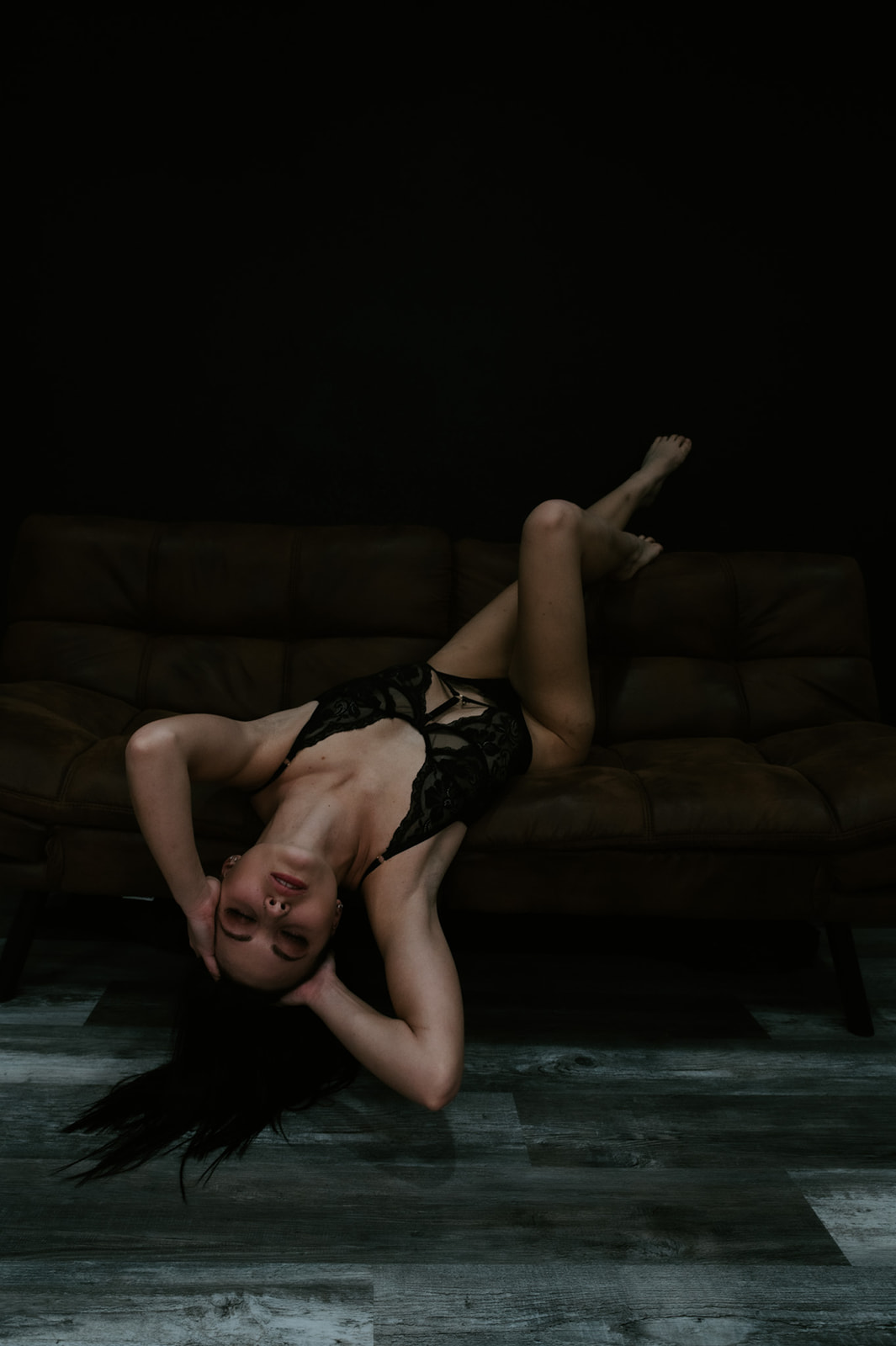 Bride posed upside down on a couch during a boudoir photo shoot, creating a dramatic and artistic composition