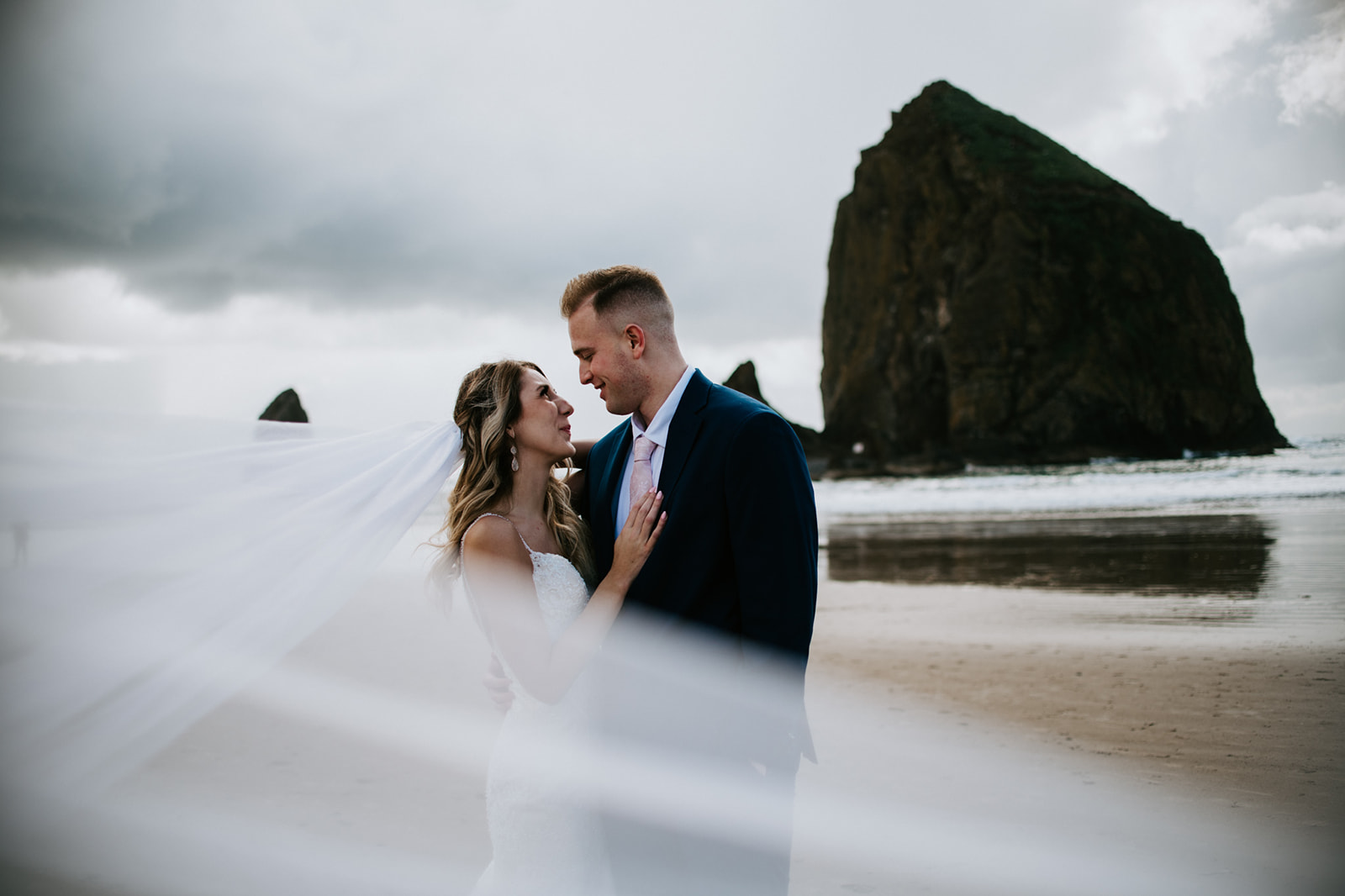 Couple smiling at one another after their intimate oregon elopement as bride's veil blows in the wind. 