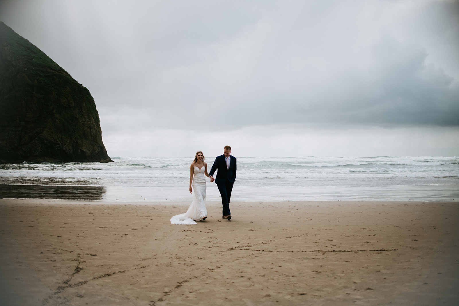 Couple walks along the shoreline of Cannon Beach after their intimate Oregon elopement. 
