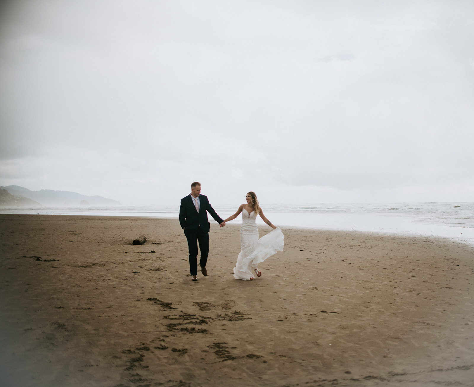 Couple walks together having fun on the beach after their intimate wedding on the beach in Oregon. 