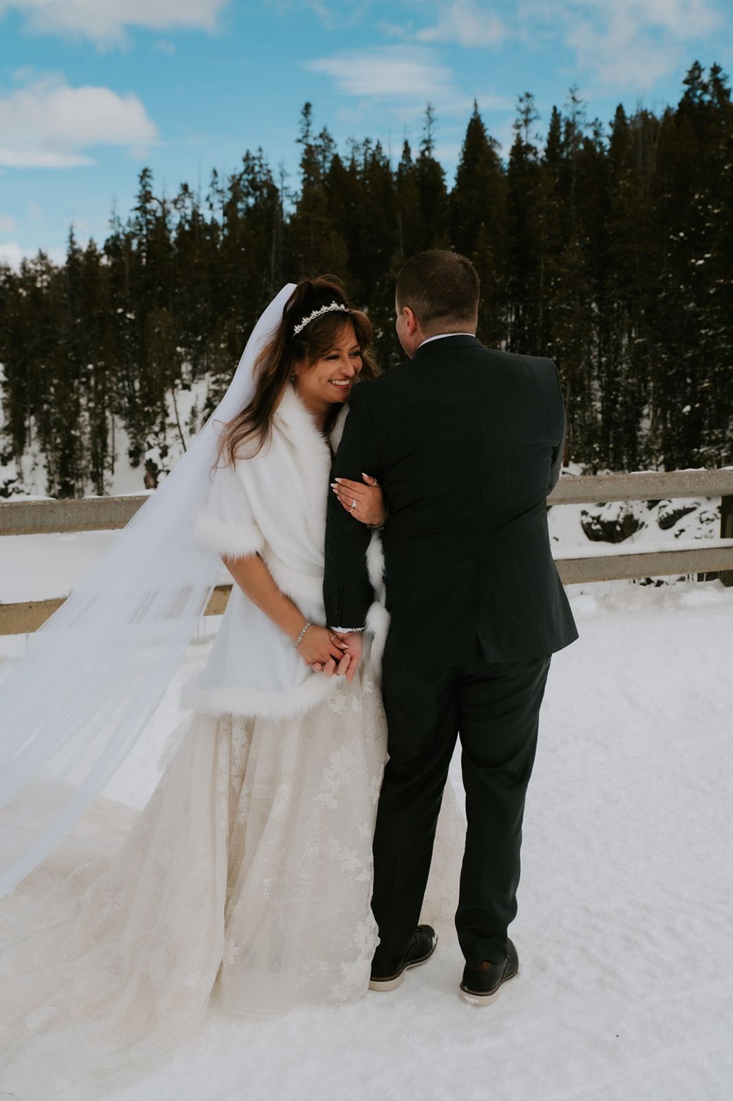 Bride laughing as she stands close to her groom on a snowy bridge, featured in their intimate elopement video.