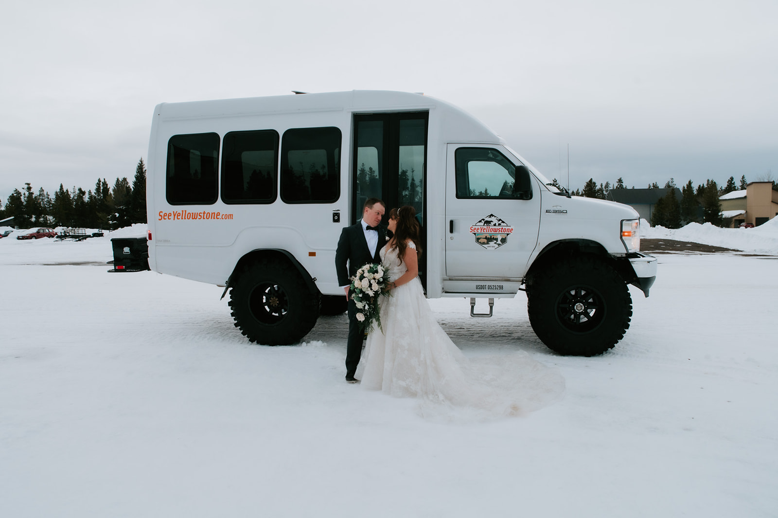 Newlyweds embracing in front of a See Yellowstone tour vehicle after their winter elopement video adventure.
