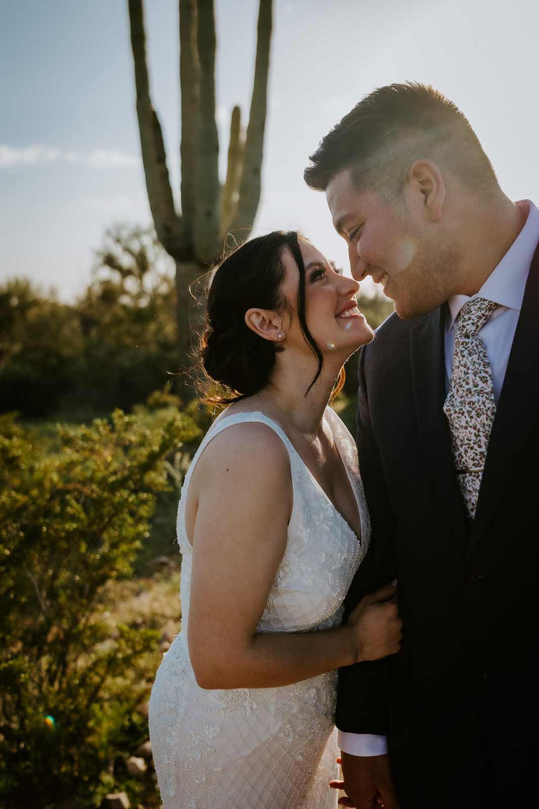 Golden hour Arizona elopement portrait with bride and groom smiling beneath a tall saguaro cactus