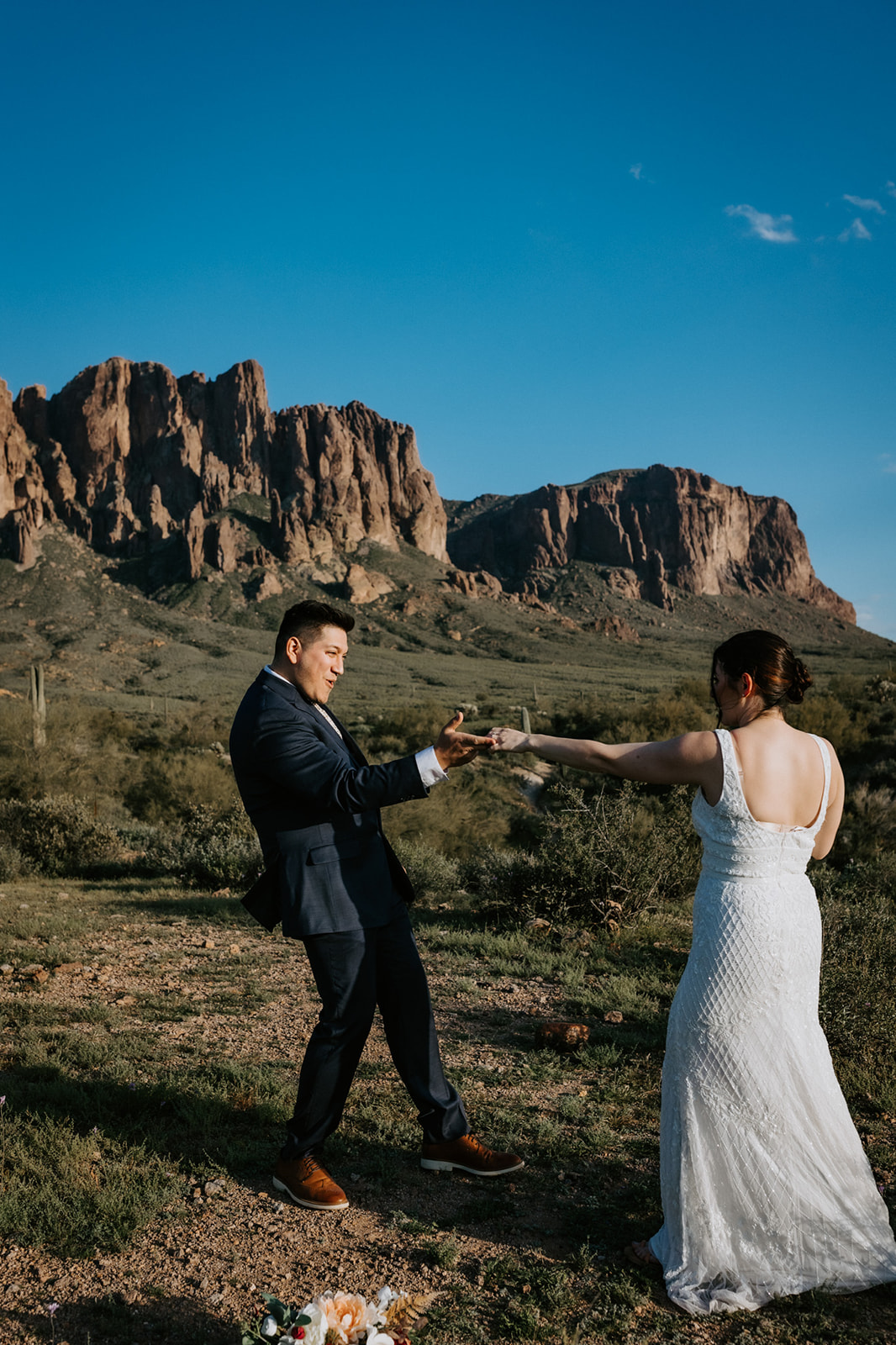 Playful Arizona elopement moment as groom spins bride in the desert with rugged mountain cliffs behind them