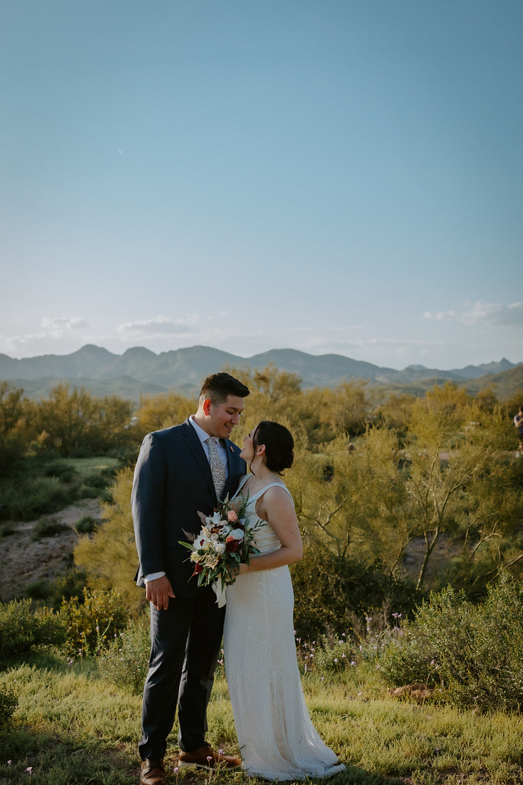 Moody Arizona elopement scene with couple standing on rock ledge under dark monsoon clouds