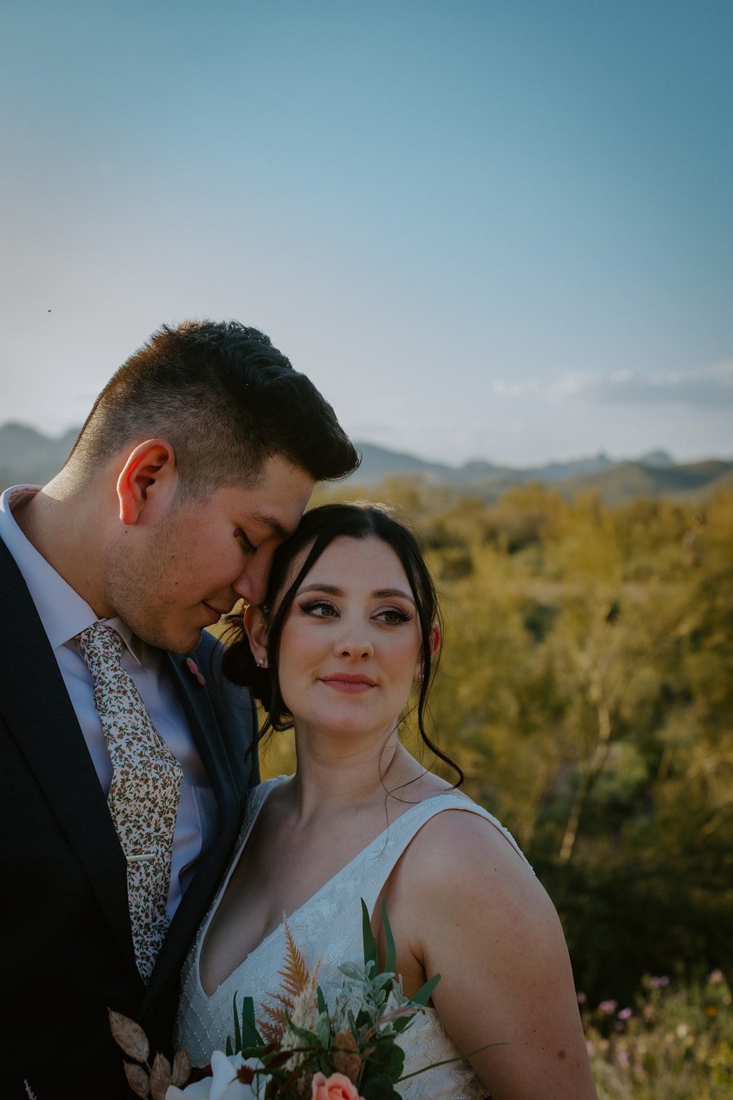Close-up portrait of bride and groom sharing a quiet moment in the desert with soft evening light