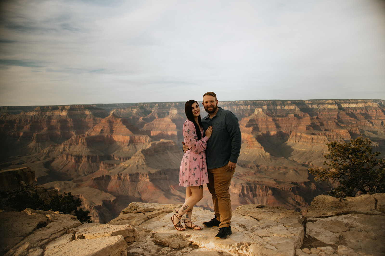 Arizona elopement portrait at the Grand Canyon with couple standing on rocky ledge above sweeping canyon views