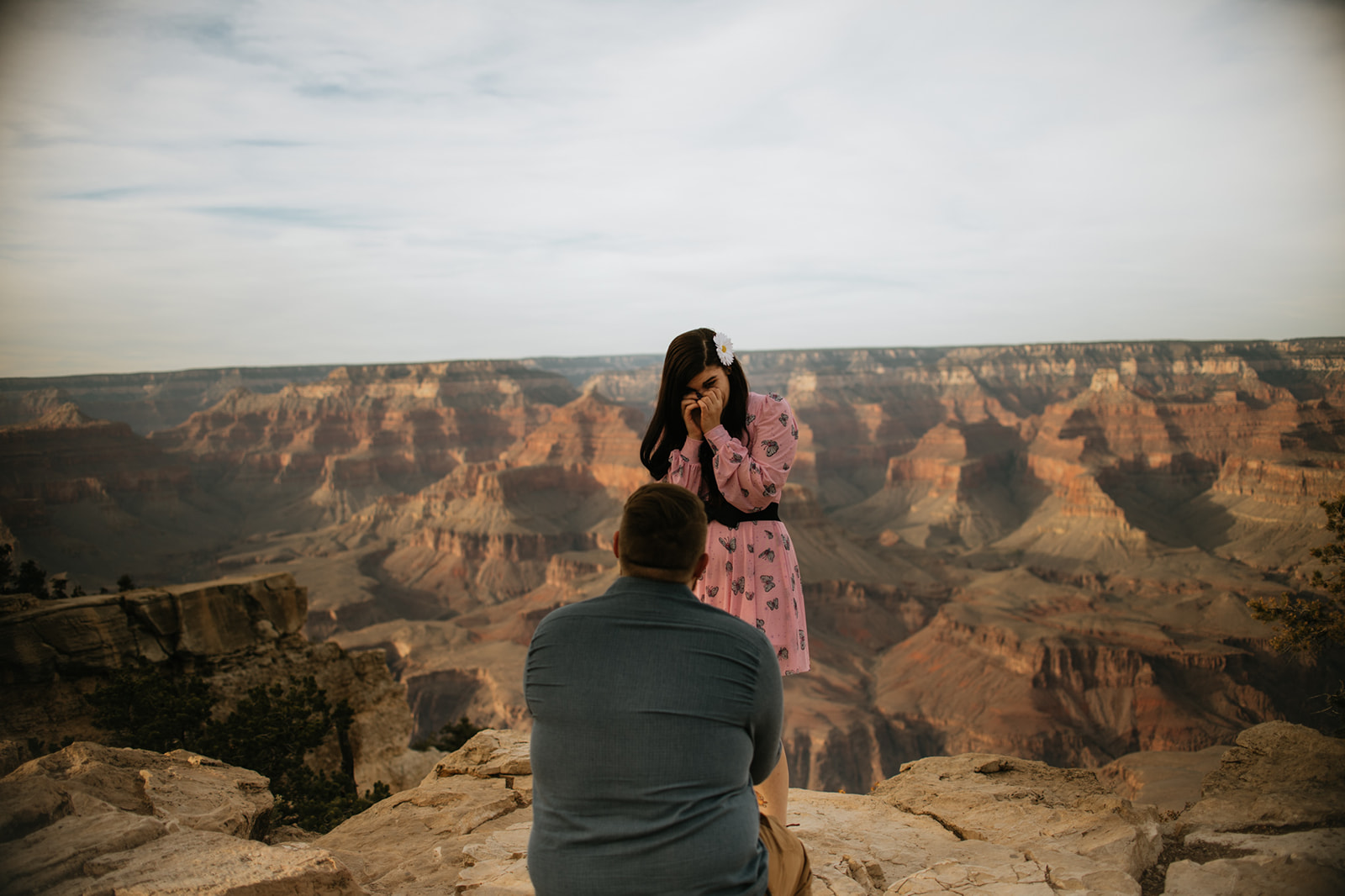 Emotional proposal moment at Grand Canyon overlook with canyon layers glowing behind the couple