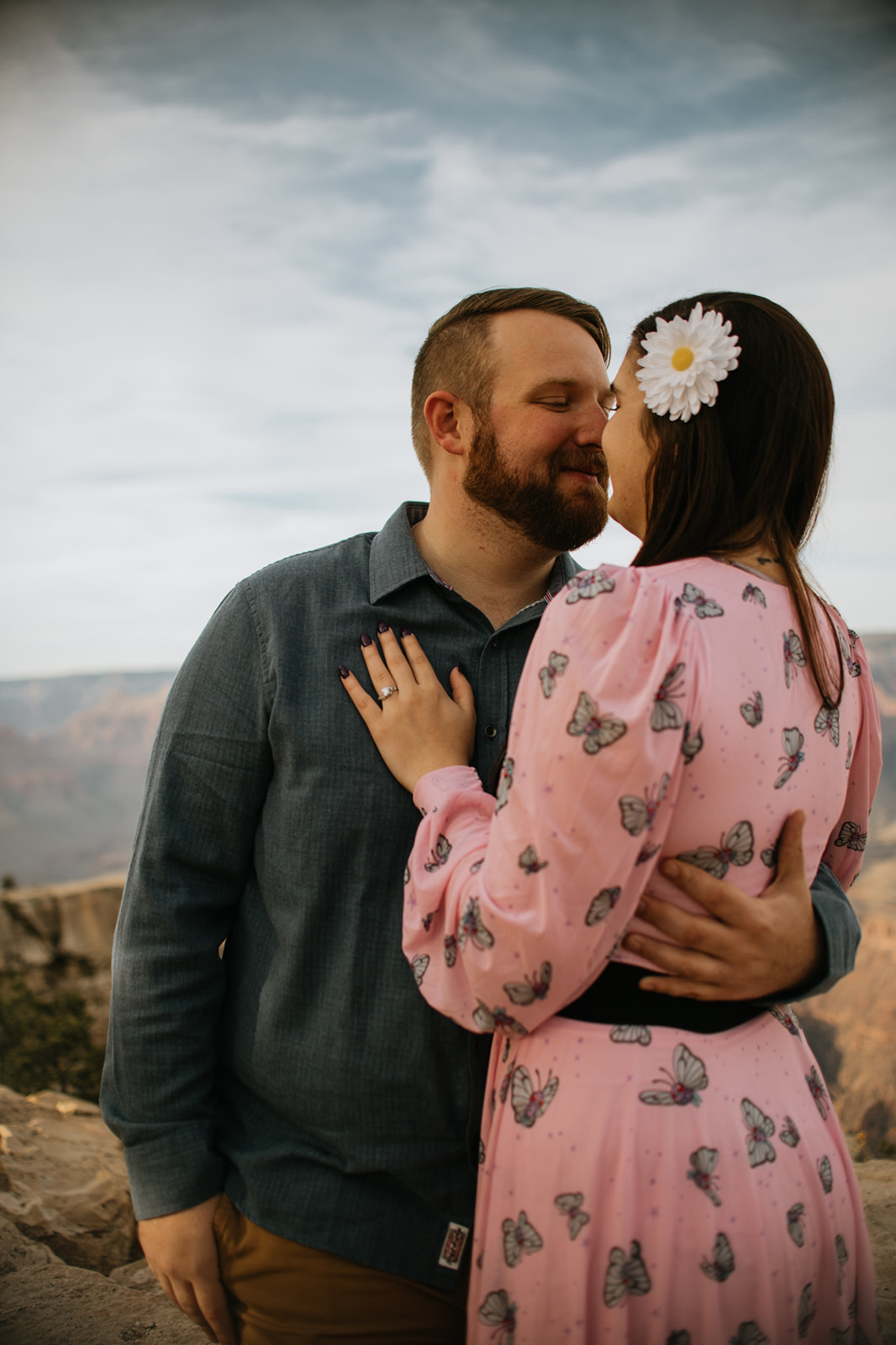Close-up of couple sharing a quiet kiss at the Grand Canyon rim, layered canyon walls fading into the distance
