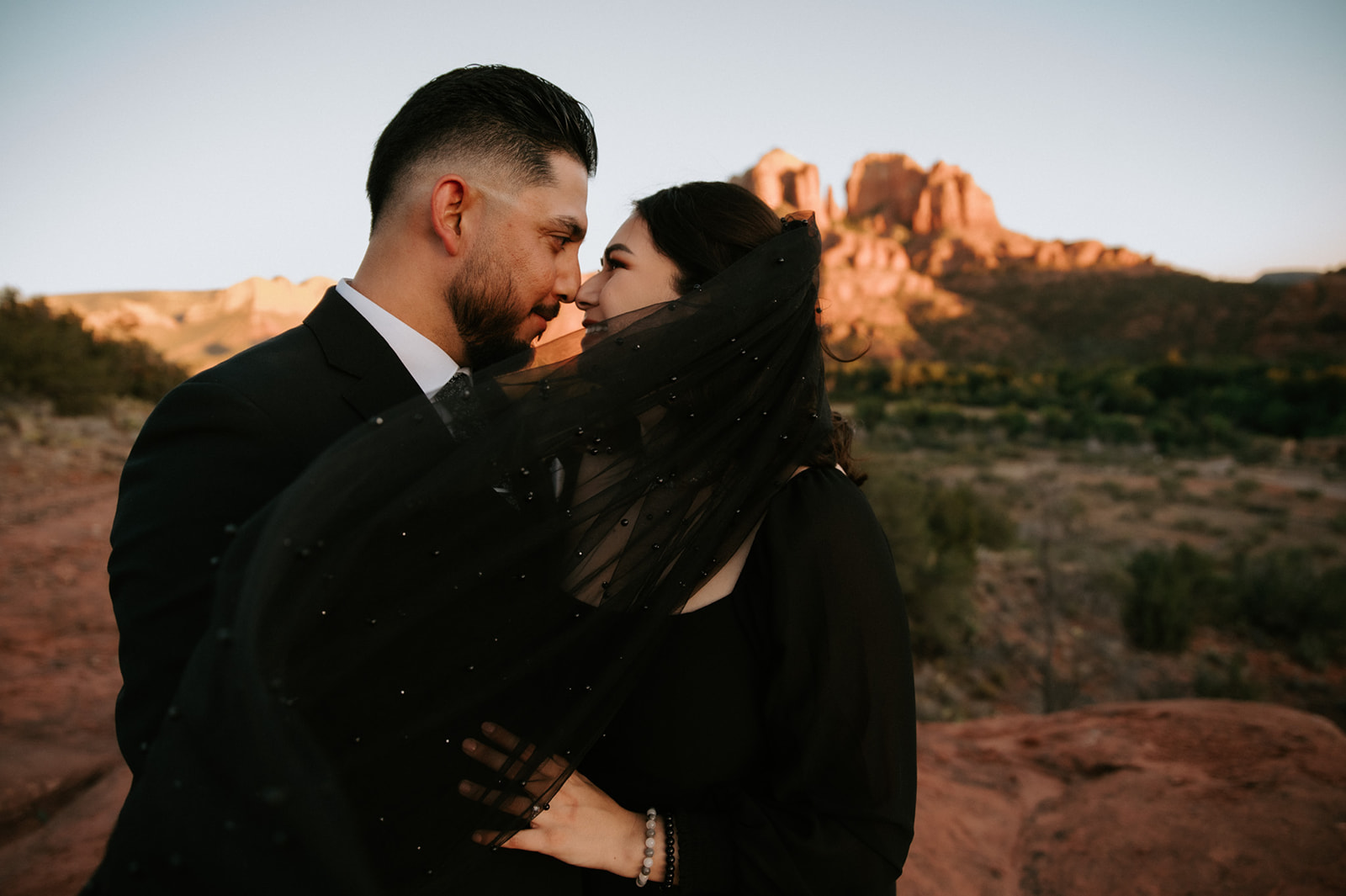 Intimate Arizona elopement moment in Sedona as bride’s veil lifts in the breeze against glowing red rock backdrop