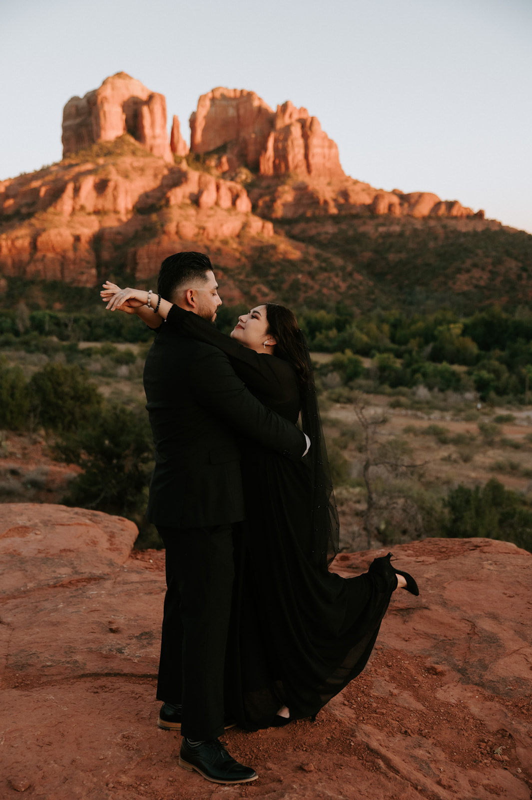 Arizona elopement in Sedona with couple embracing on red rock overlook beneath Cathedral Rock at golden hour