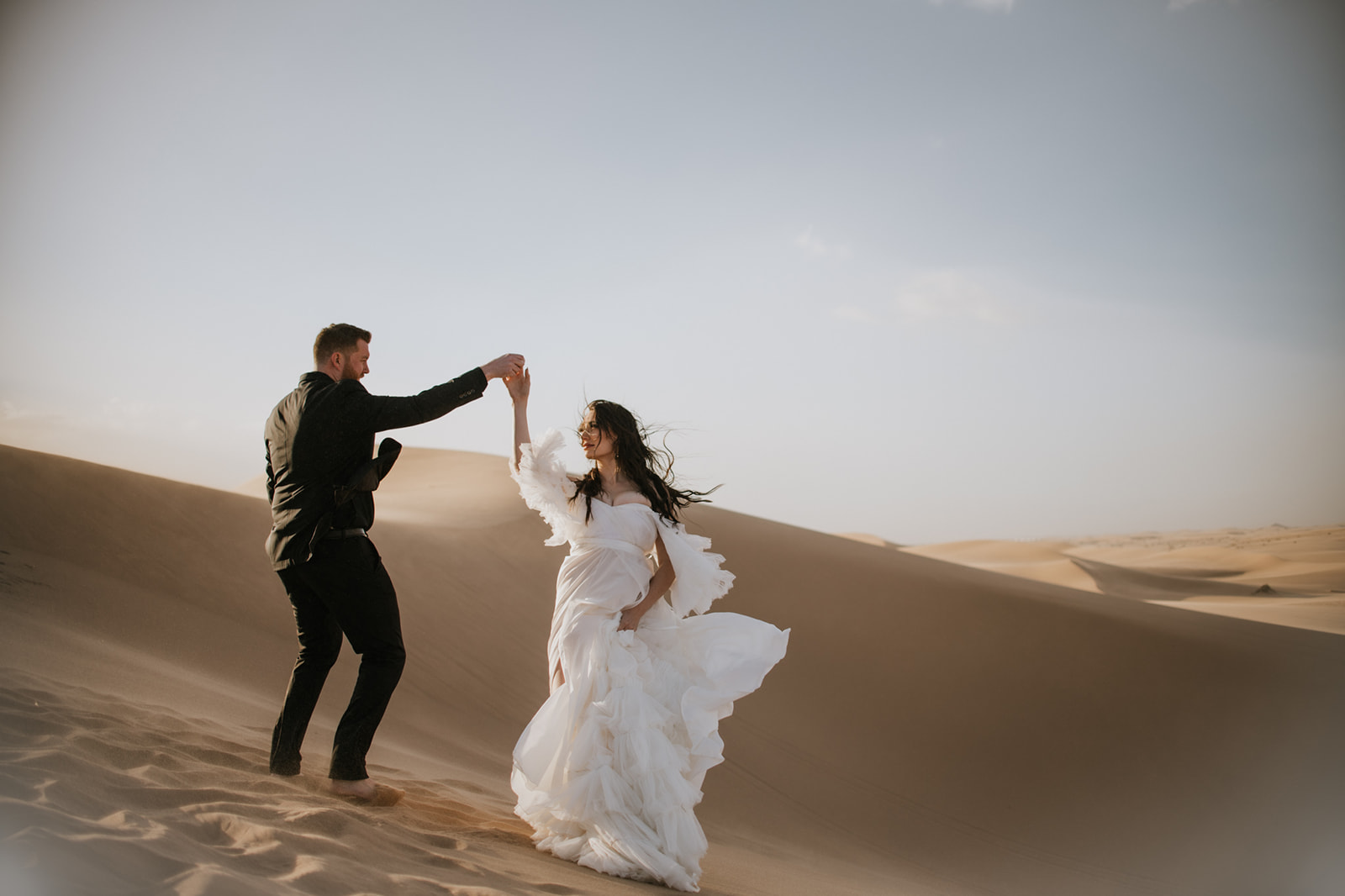 Couple sharing a quiet embrace in the sand dunes during their destination elopement.

