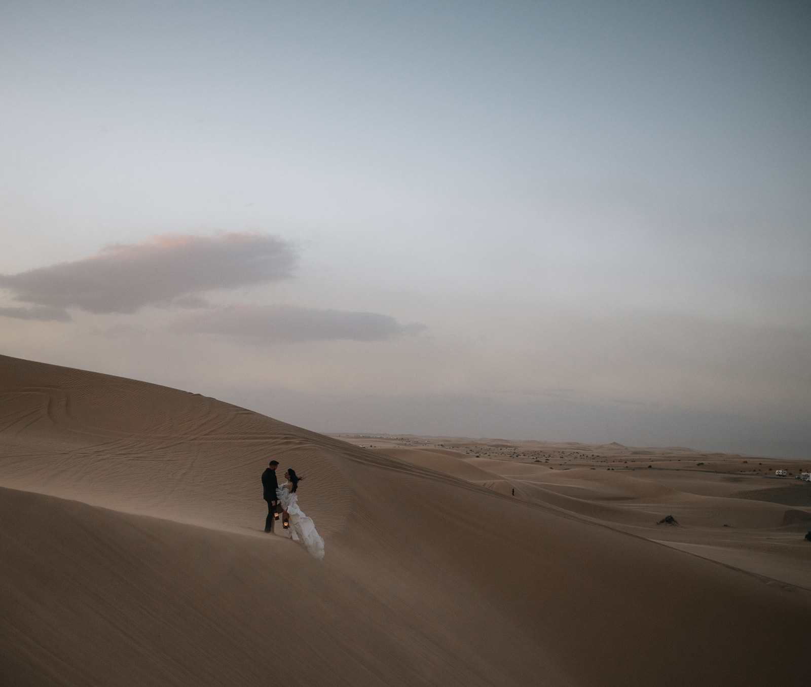 Wide view of a couple standing together on a massive sand dune during an intimate destination elopement.
