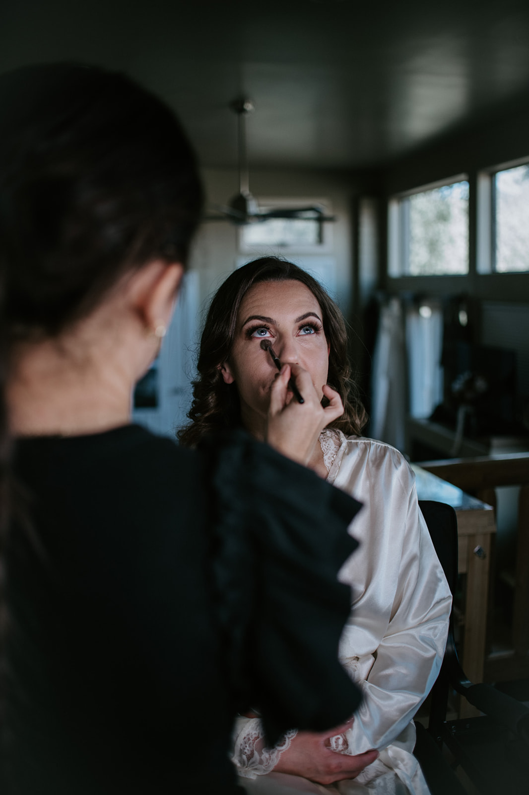 Bride getting makeup done in natural window light inside an Airbnb before her elopement in Arizona
