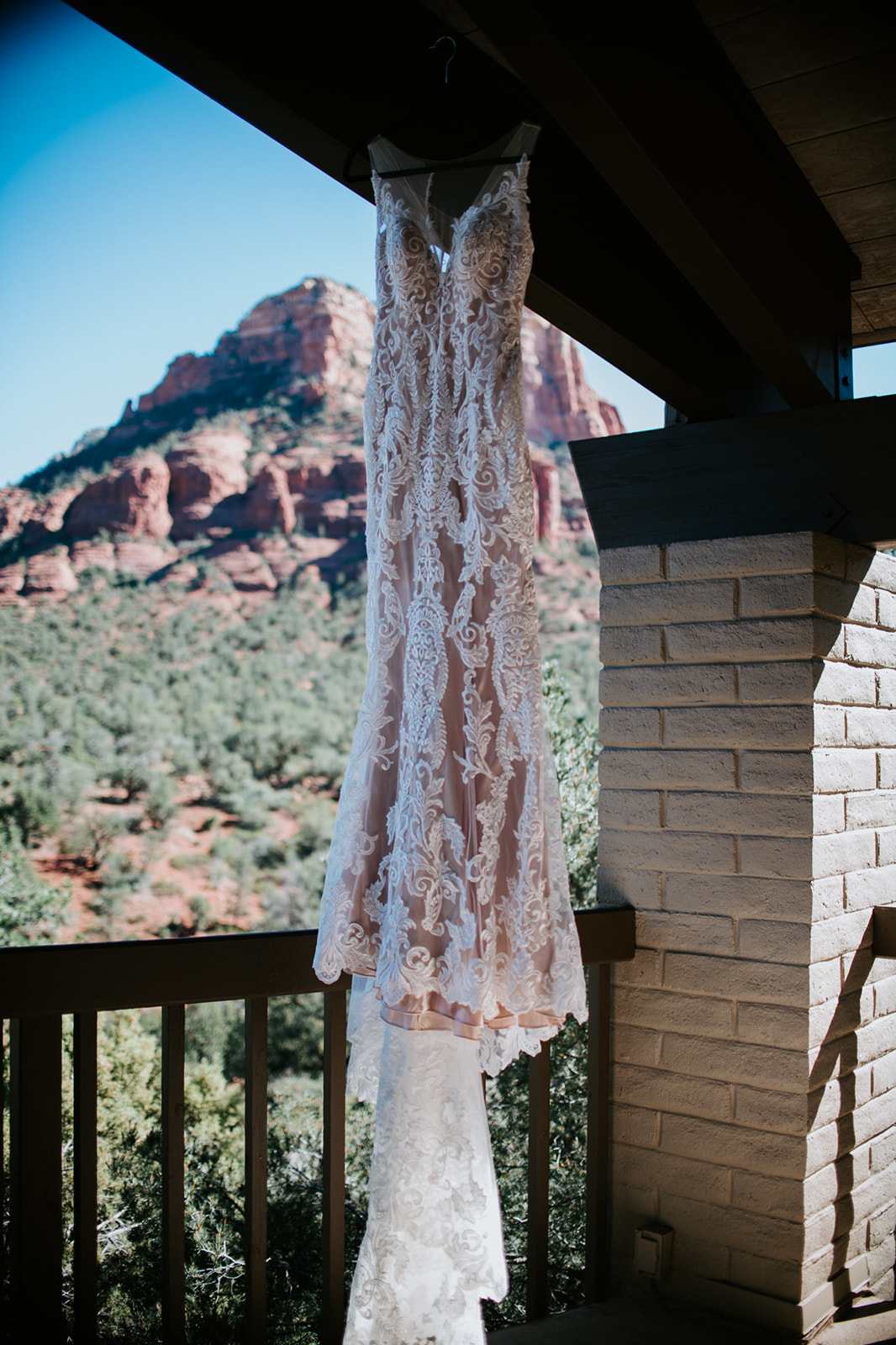 Lace wedding dress hanging on a balcony with Sedona red rocks in the background during an elopement in Arizona
