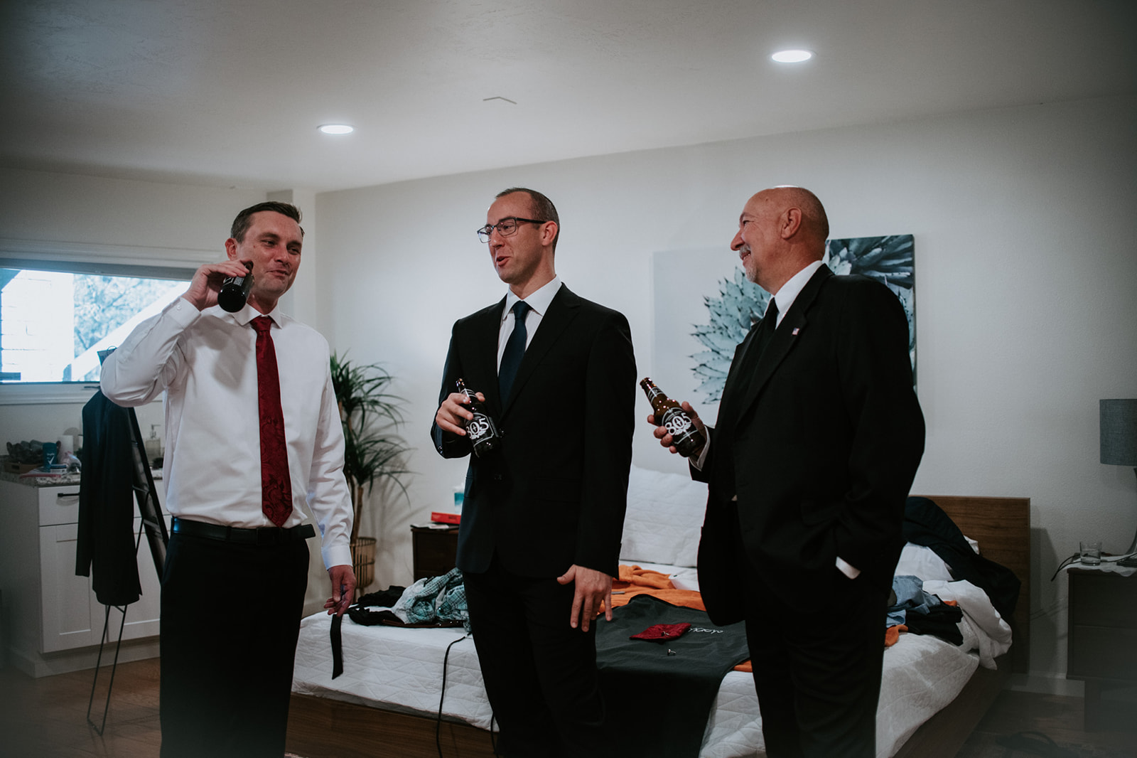 Groom and two family members sharing a drink and getting ready inside a modern Airbnb before an elopement in Arizona
