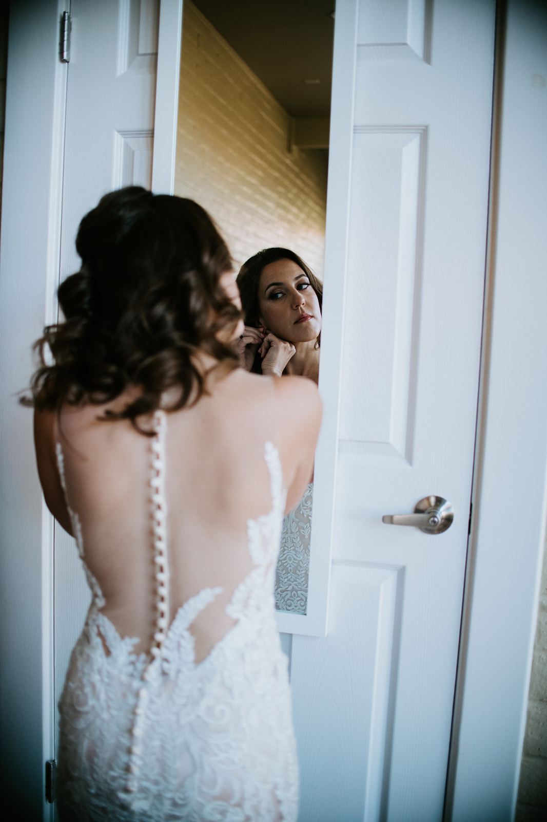 Bride putting on earrings in front of a mirror inside an Airbnb before her elopement in Arizona
