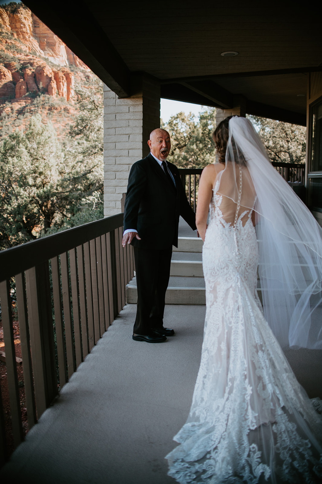 Emotional first look moment between bride and father on a balcony with red rock views

