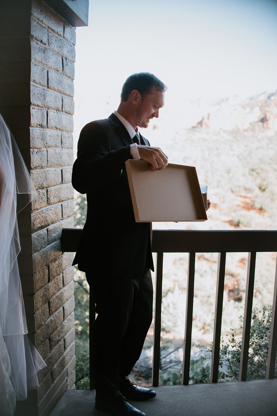 Groom opening a gift box on a Sedona Airbnb balcony before the ceremony
