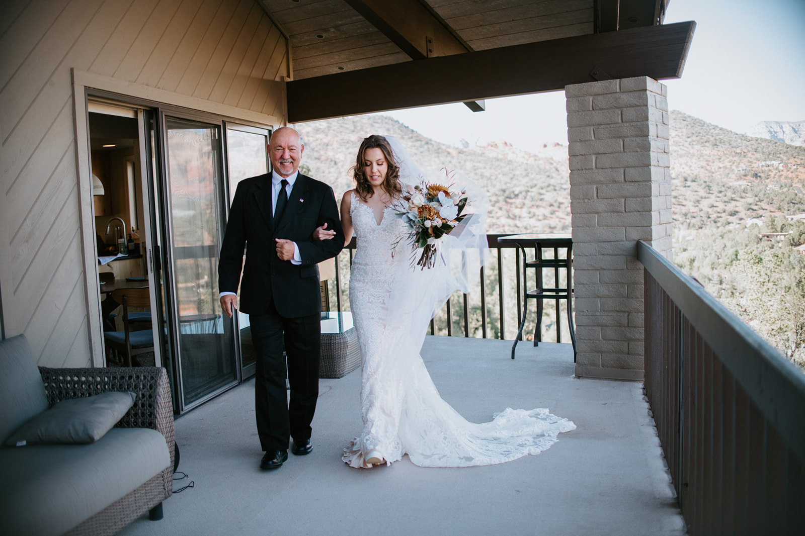 Bride walking arm in arm with her father on a Sedona Airbnb balcony before her elopement in Arizona
