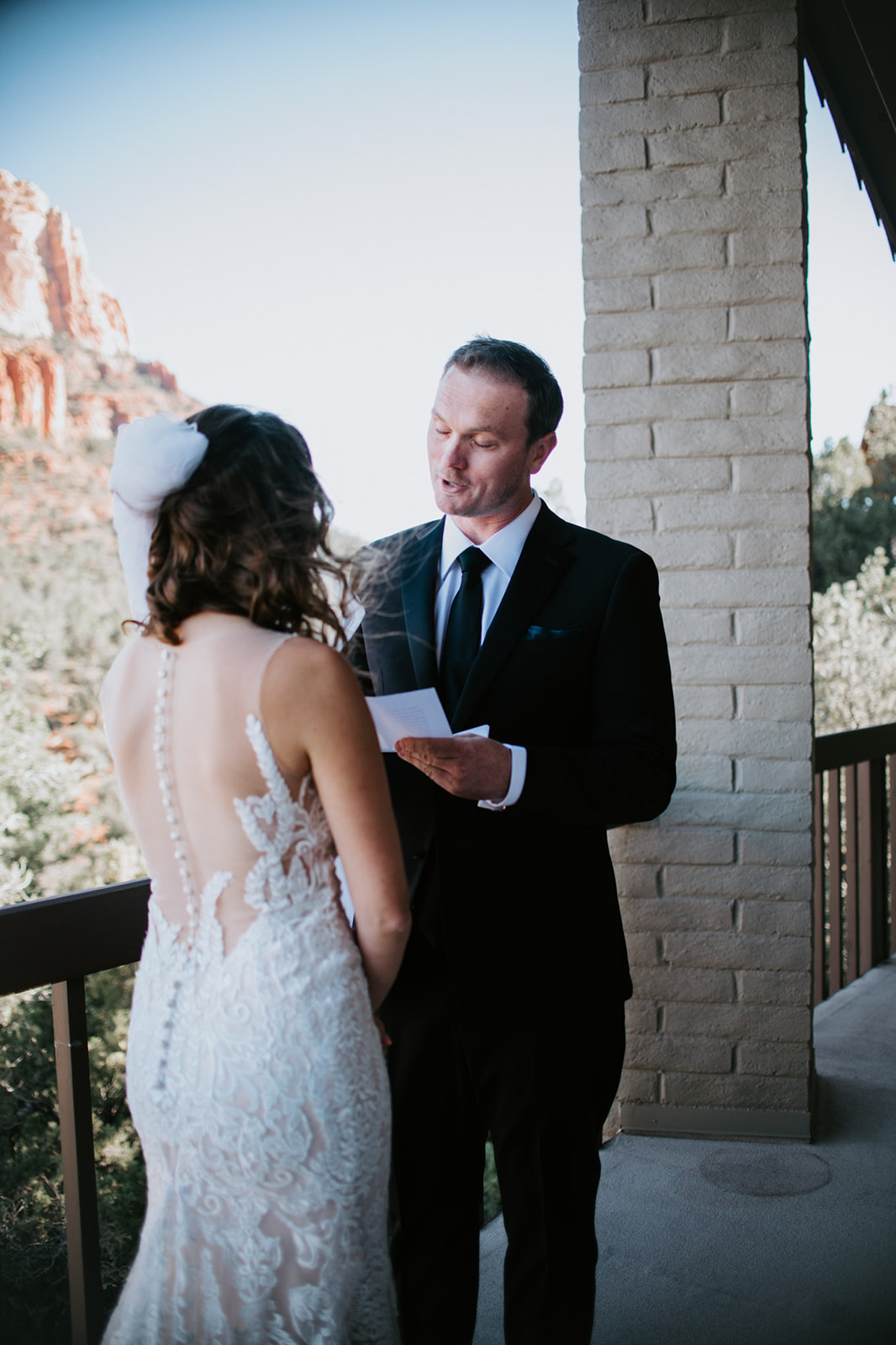 Groom reading vows to his partner on a private Airbnb balcony with mountain views
