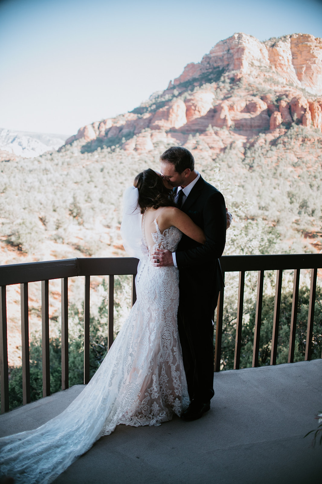 Couple sharing a kiss on a balcony with sweeping red rock scenery during their elopement in Arizona
