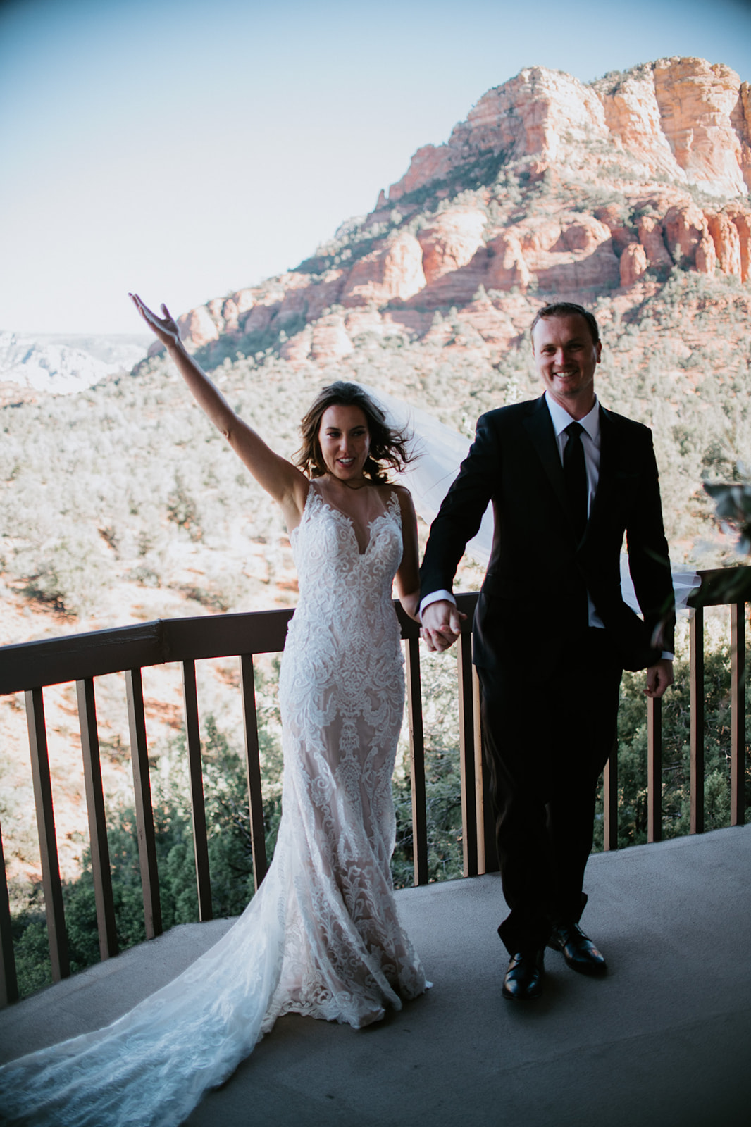 Bride raising her arm in celebration while walking with her partner after their elopement in Arizona

