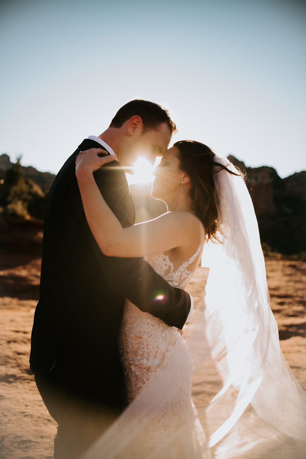 Backlit couple embracing at sunset with glowing veil during an Arizona desert elopement
