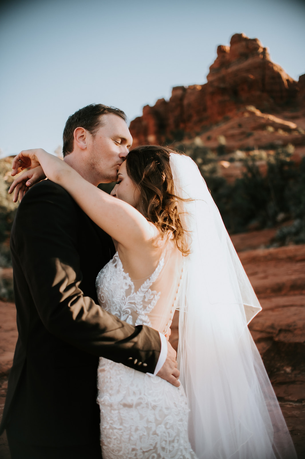 Close-up of couple sharing an intimate moment with Sedona red rocks behind them
