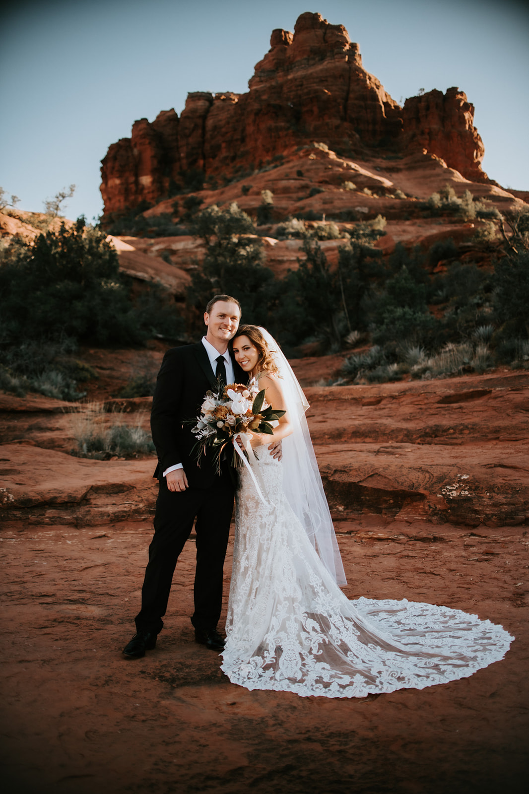 Bride and groom standing together on red rock landscape after their elopement in Arizona
