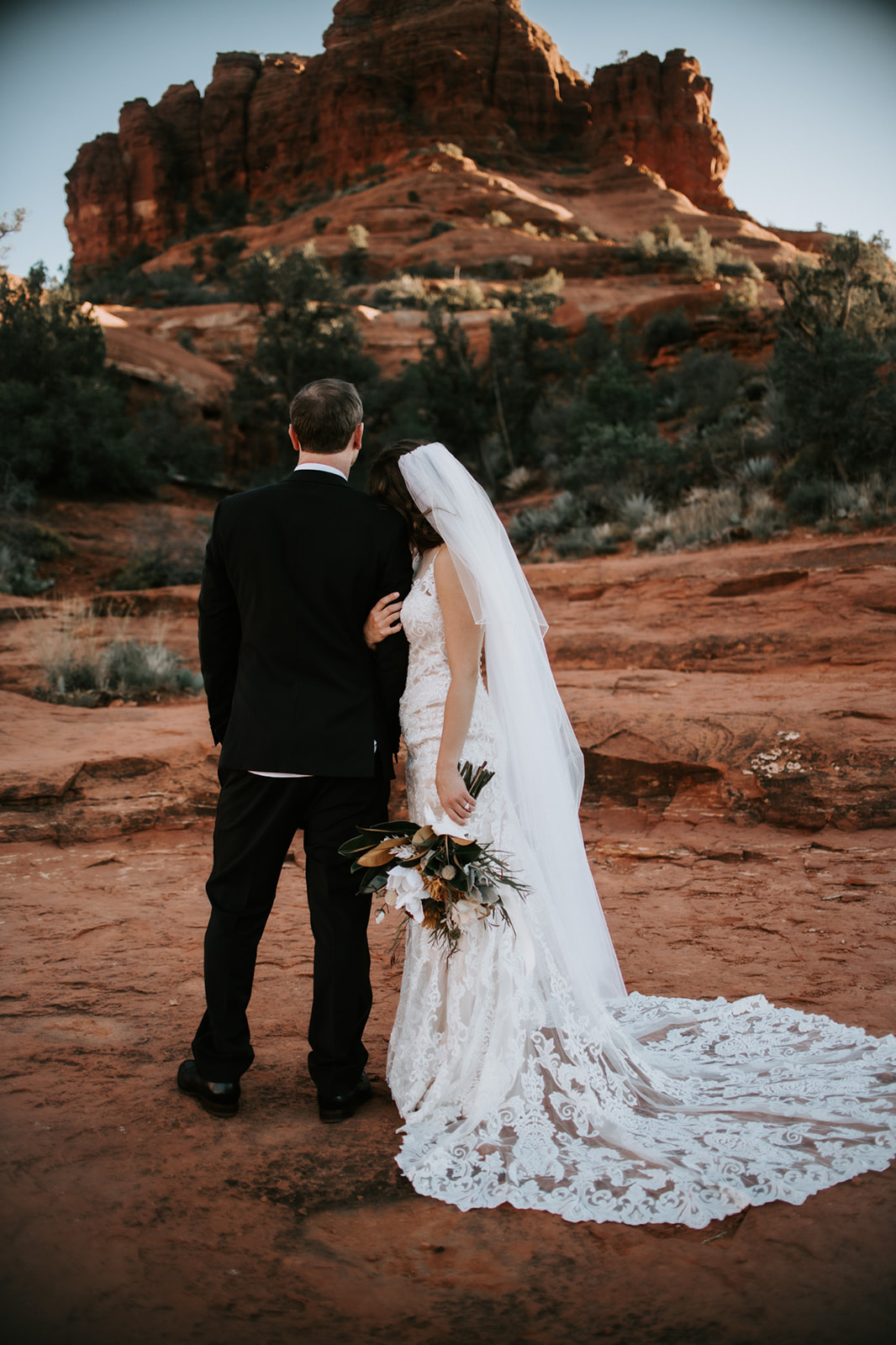 Bride and groom walking away together across red rocks after their Sedona elopement
