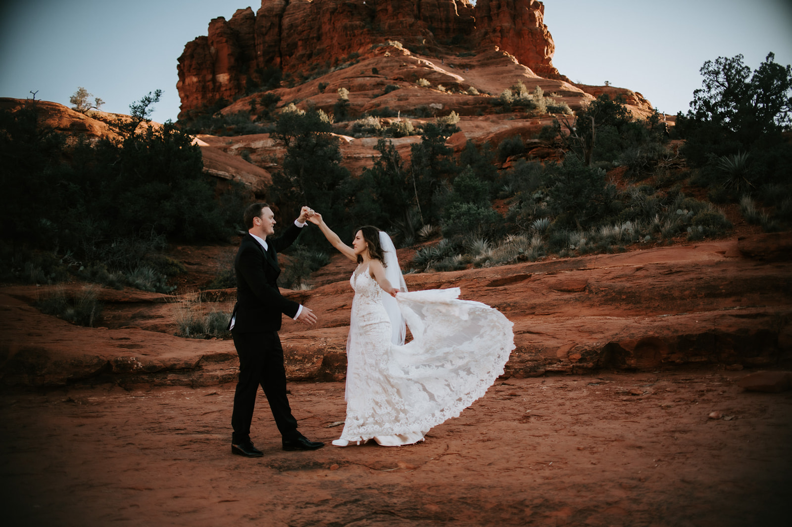 Couple dancing together on red rock terrain with flowing dress during an elopement in Arizona
