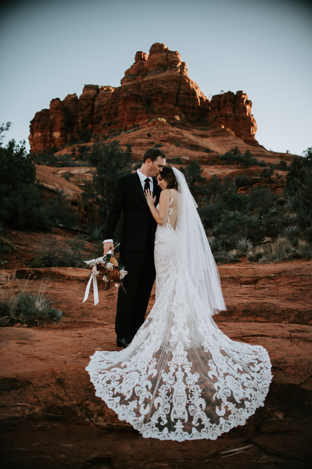 Intimate embrace between bride and groom with iconic Sedona red rock backdrop

