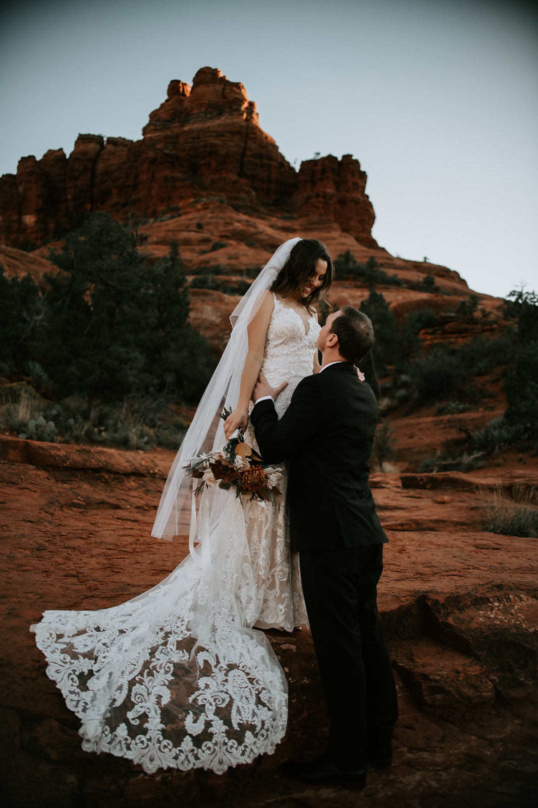 Groom lifting bride during a romantic moment on Sedona red rocks
