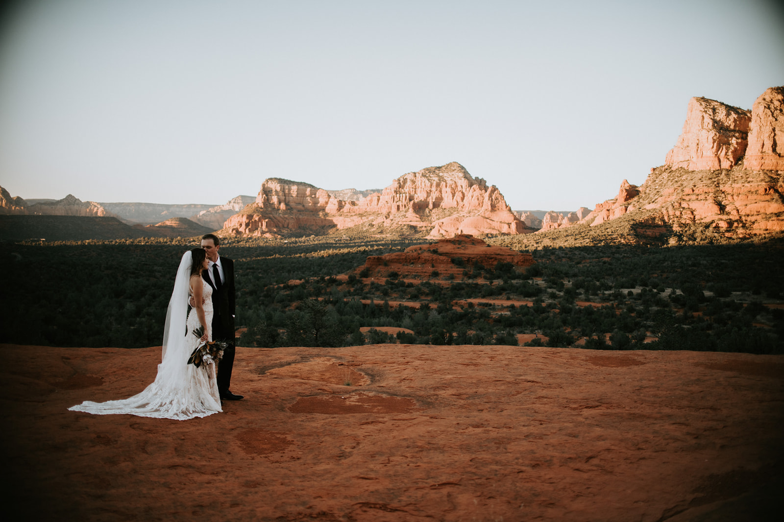 Couple standing together on a red rock overlook with sweeping Sedona landscape during their elopement in Arizona
