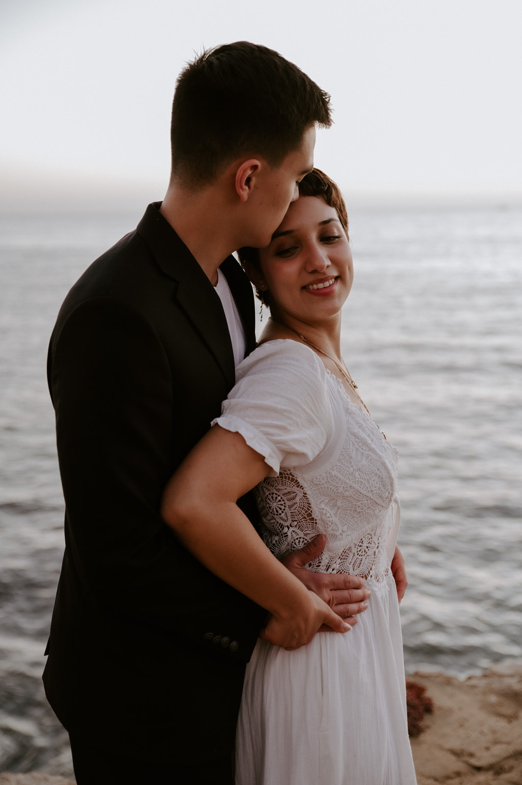 Groom kissing bride’s temple as she smiles softly, a calm and connected moment during their elopement checklist experience.
