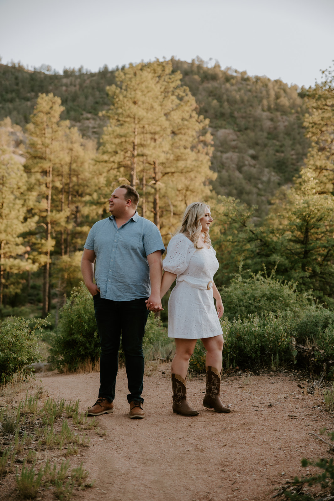 Couple holding hands and looking in opposite directions on a scenic mountain trail in Flagstaff
