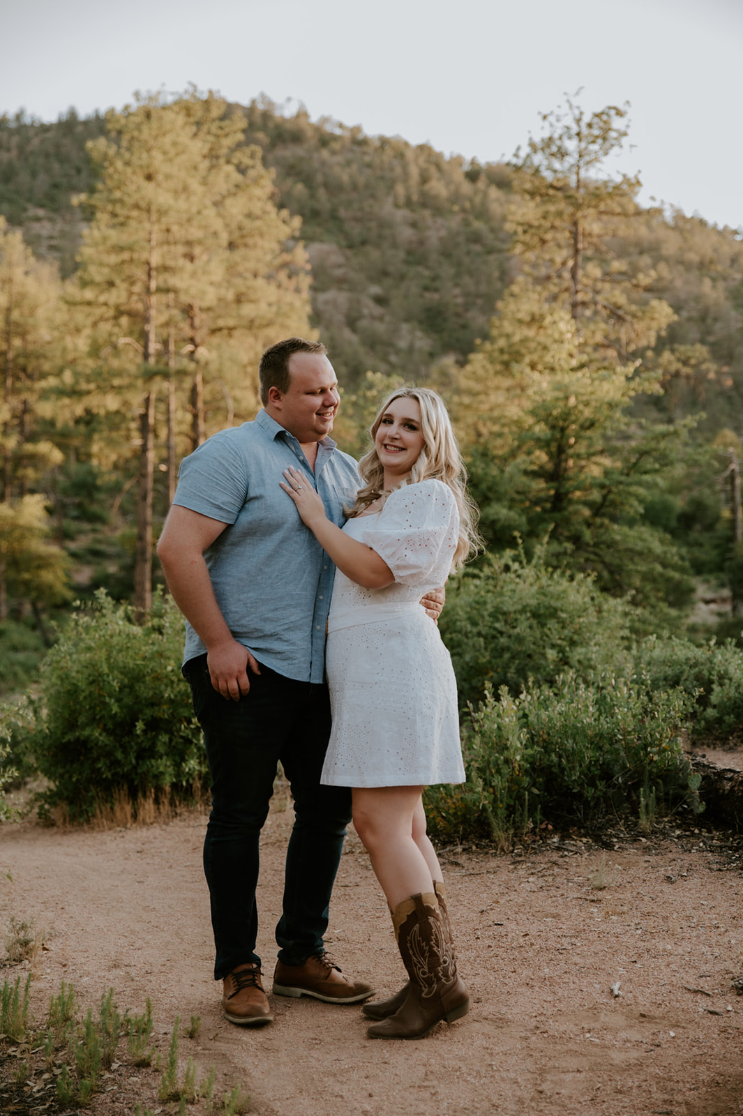 Couple standing together on a dirt trail with mountain views and pine trees in Flagstaff

