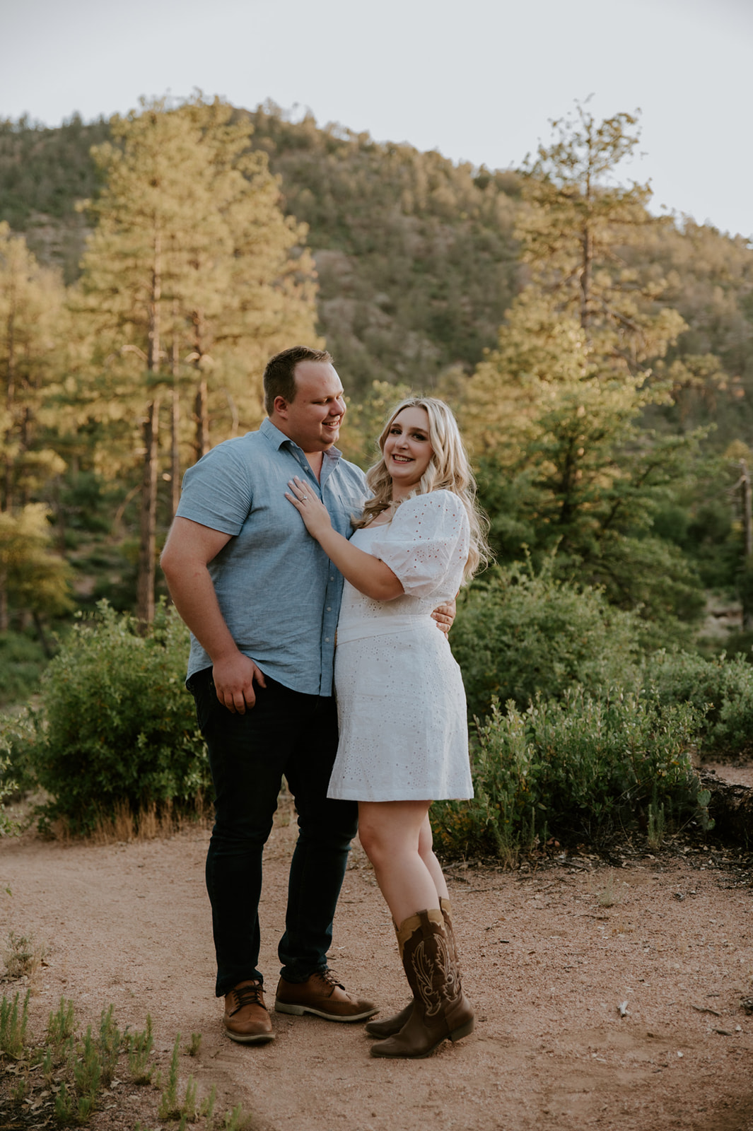 Couple standing together on a dirt path surrounded by trees and greenery during a relaxed adventure elopement session
