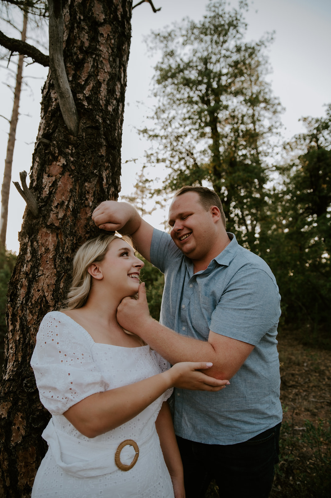 Playful, close moment as a couple smiles at each other beside a tree during an adventure elopement session
