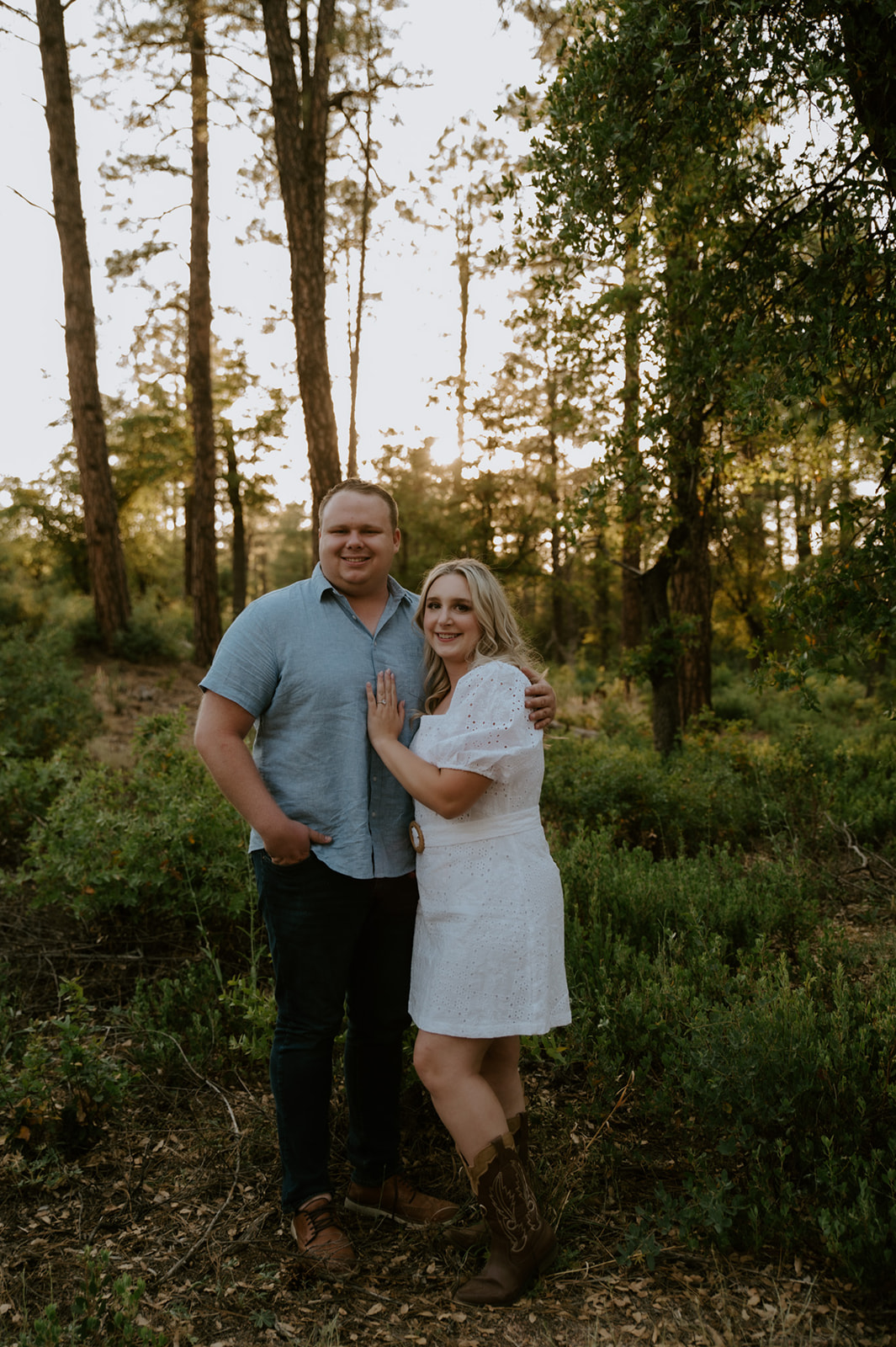 Couple smiling at the camera while standing together in a forest setting, capturing a relaxed adventure elopement vibe
