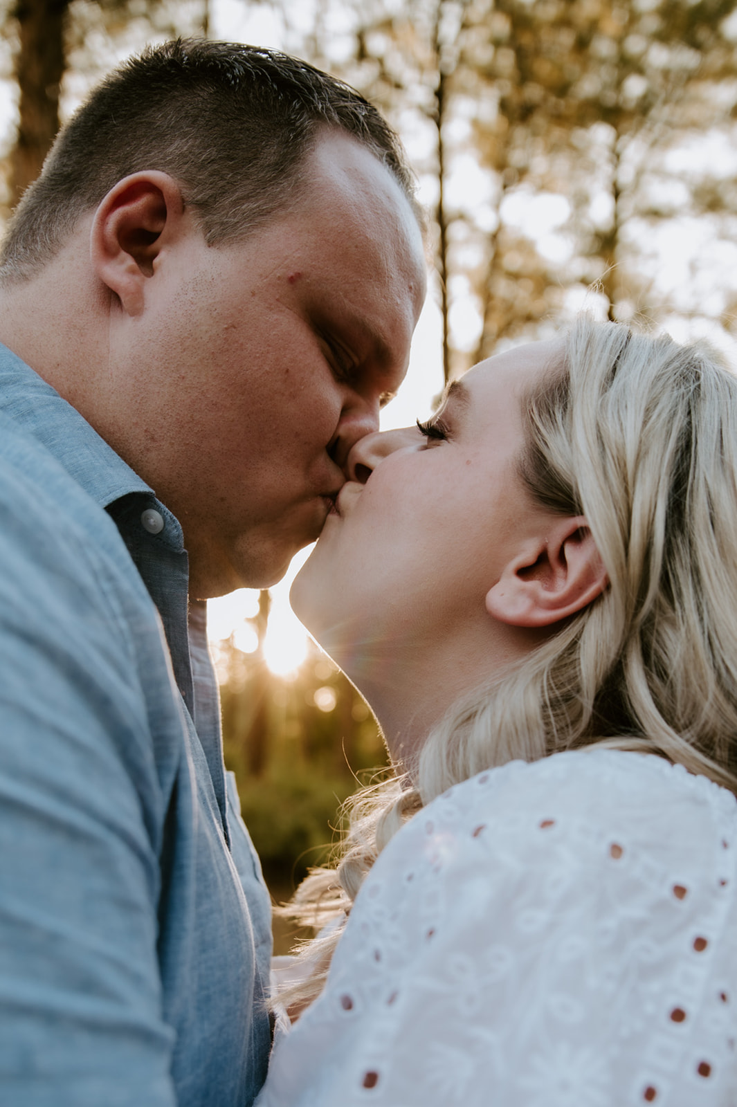 Close-up of a couple sharing a kiss with warm golden sunlight shining through the trees, perfect for adventure elopements
