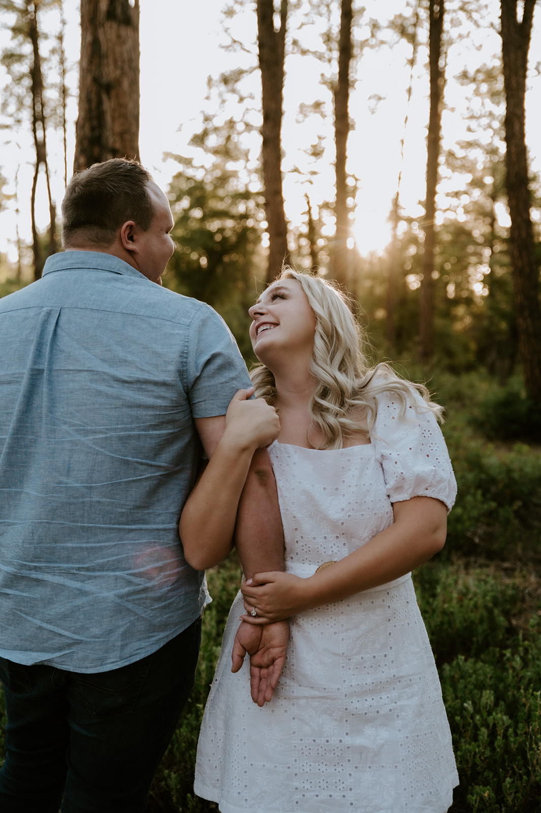Candid moment of a couple laughing together in a pine forest during golden hour, perfect for adventure elopements
