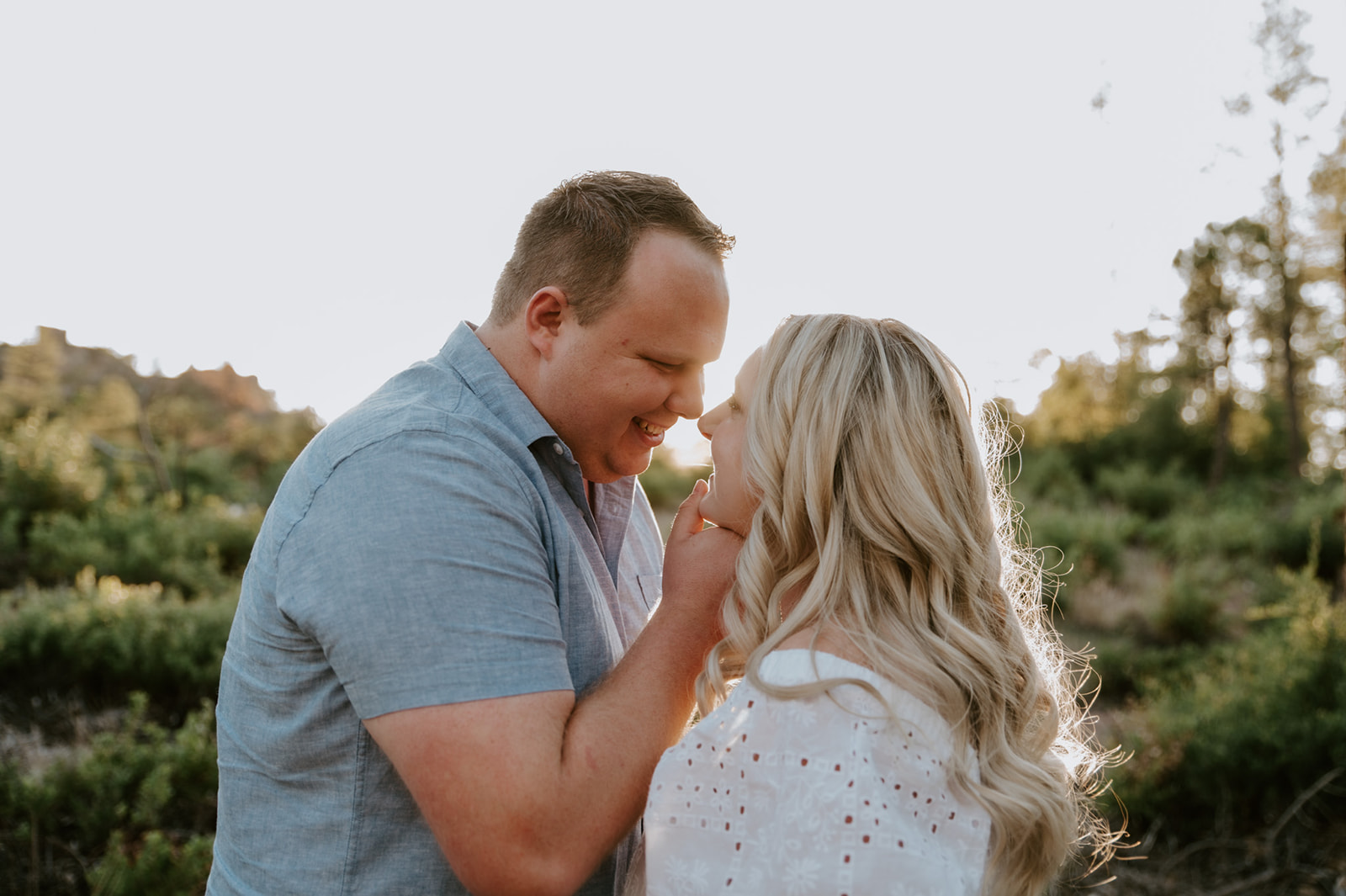 Playful, intimate moment as a couple laughs together with warm sunset light in the background
