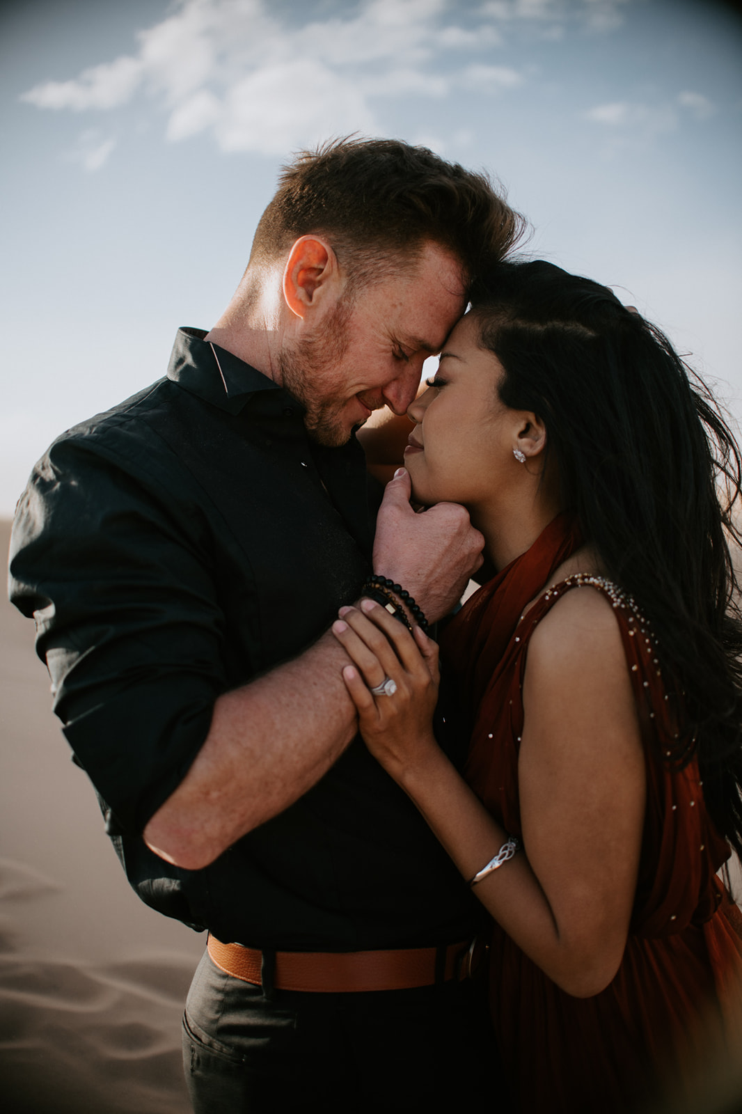 Close-up of couple leaning into each other, foreheads touching during a quiet desert moment
